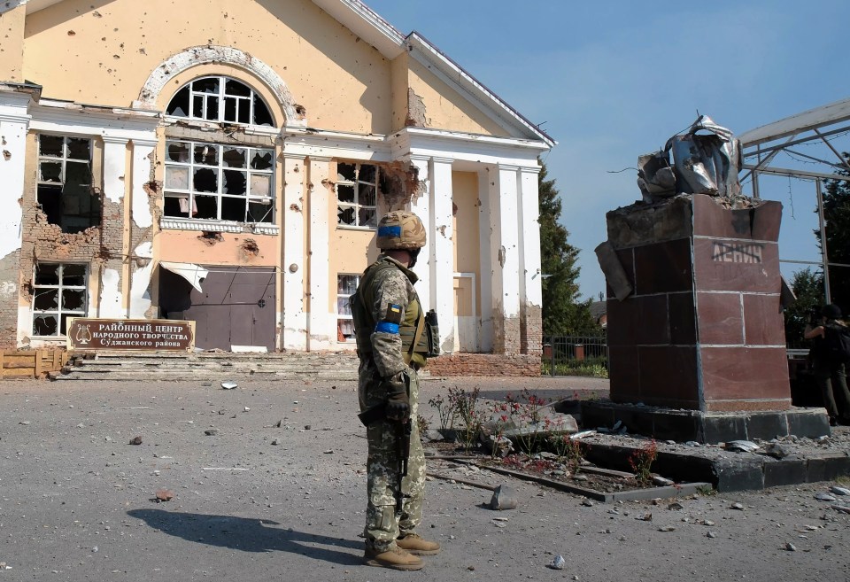 A Ukrainian troop stands in front of a building in Sudzha after capturing the key Russian city