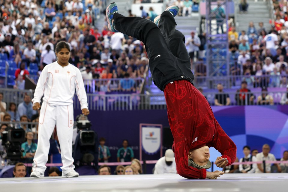 a man in a red shirt does a handstand in front of a crowd