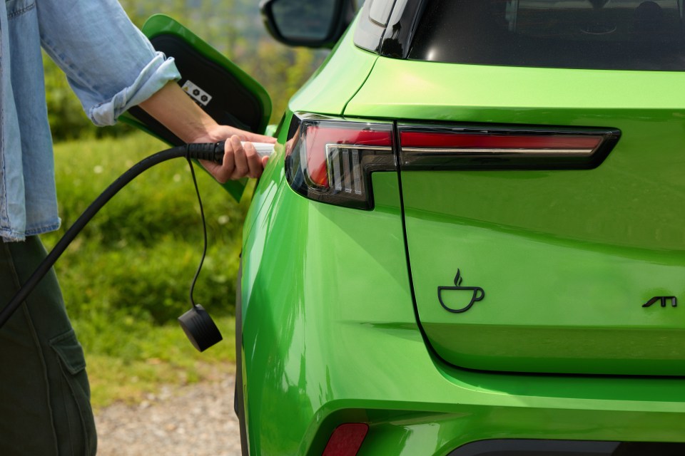 a green car is being charged by a person