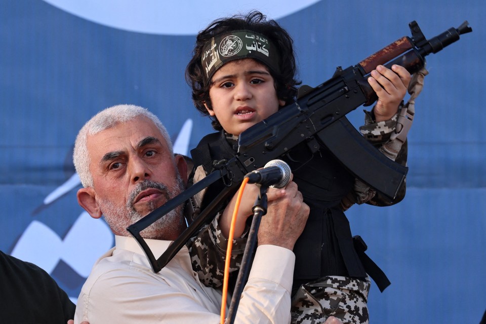 Hamas leader Yahya Sinwar holding up a child wielding a gun