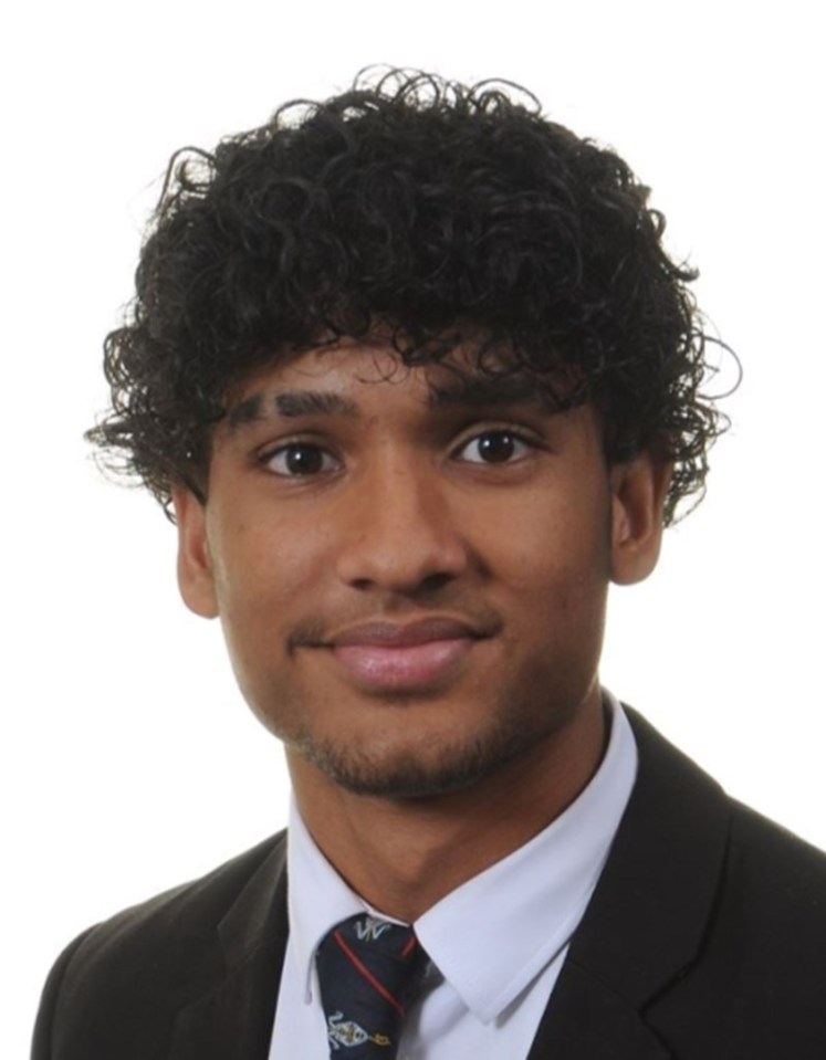 a young man with curly hair wearing a suit and tie