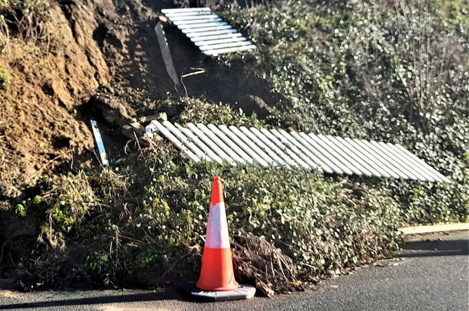 an orange and white traffic cone sits on the side of a road