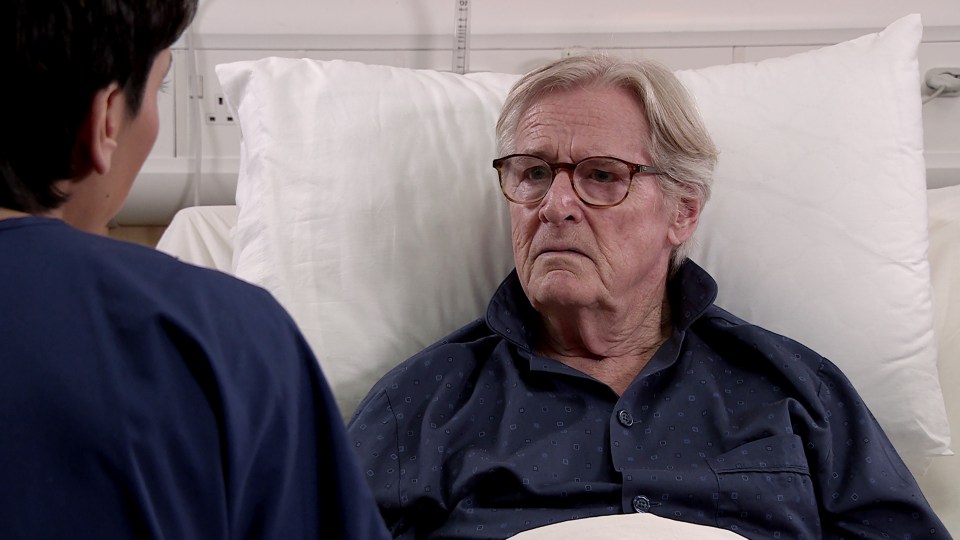 an elderly man in a hospital bed talking to a nurse