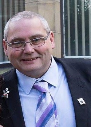 a man in a suit and tie is smiling for the camera .