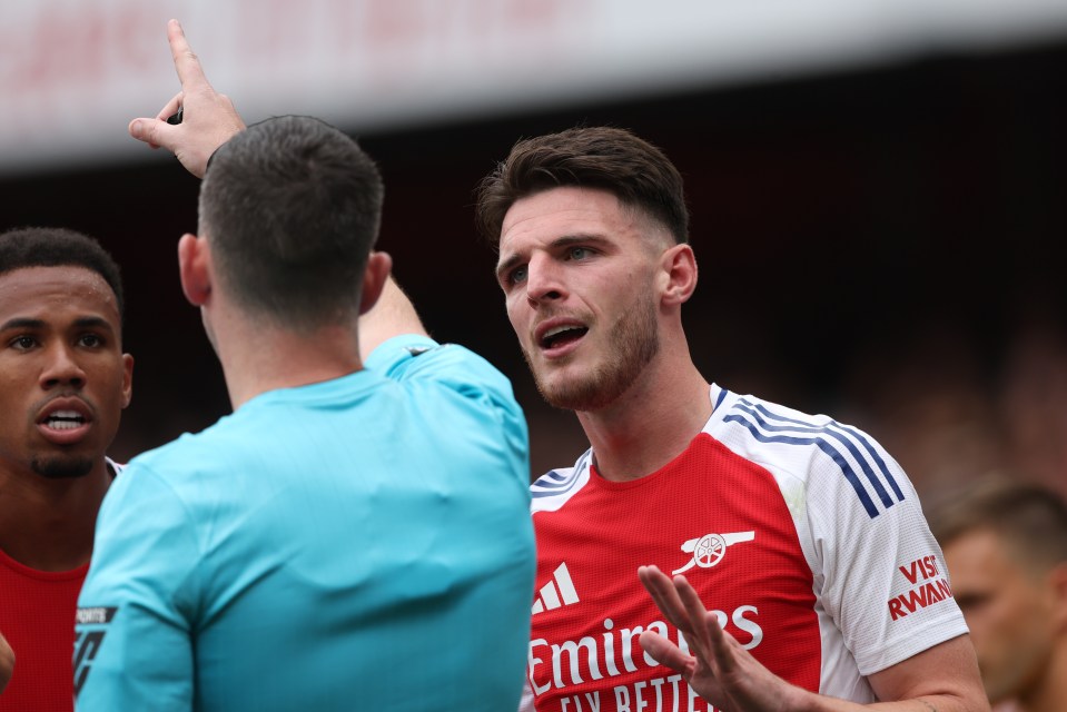 a soccer player wearing an emirates jersey talks to another player