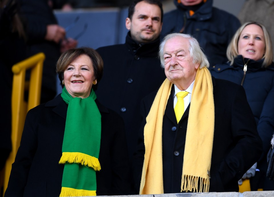 a man wearing a yellow tie and a green scarf stands next to a woman wearing a green scarf