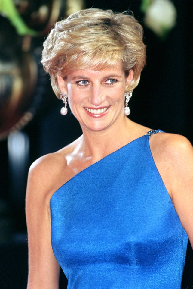 a woman wearing a blue dress and pearl earrings smiles