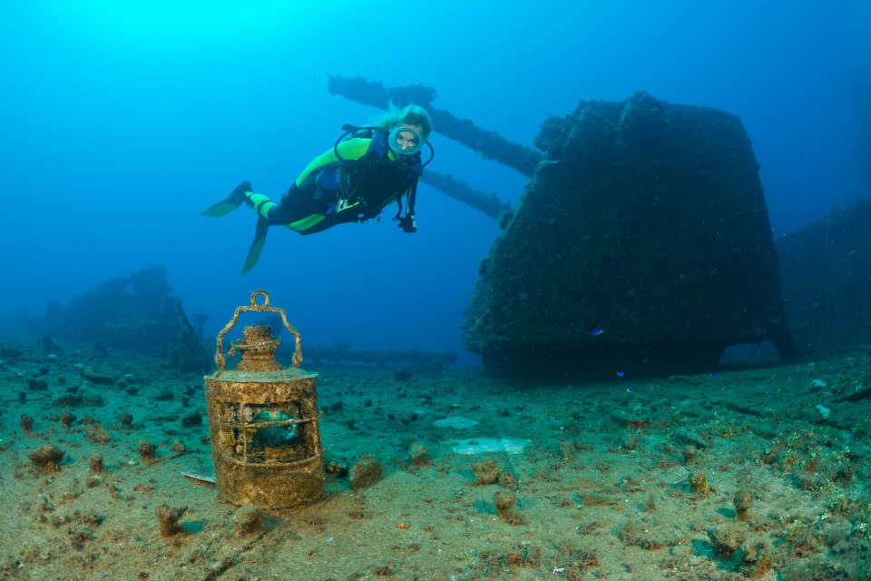 a scuba diver is swimming in the ocean near a lantern