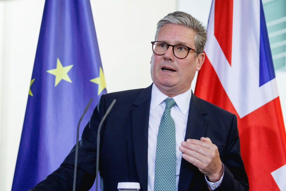 a man in a suit and tie stands in front of two flags