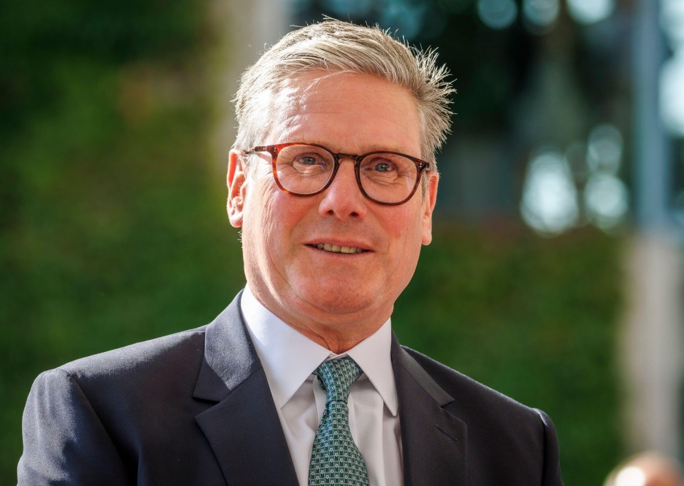 a man wearing glasses and a suit smiles for the camera