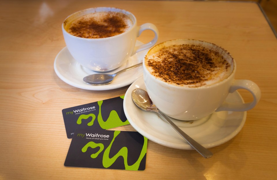 two cups of coffee and two waitrose cards on a table