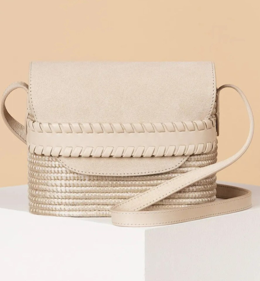 a white purse with a braided strap sits on a white cube