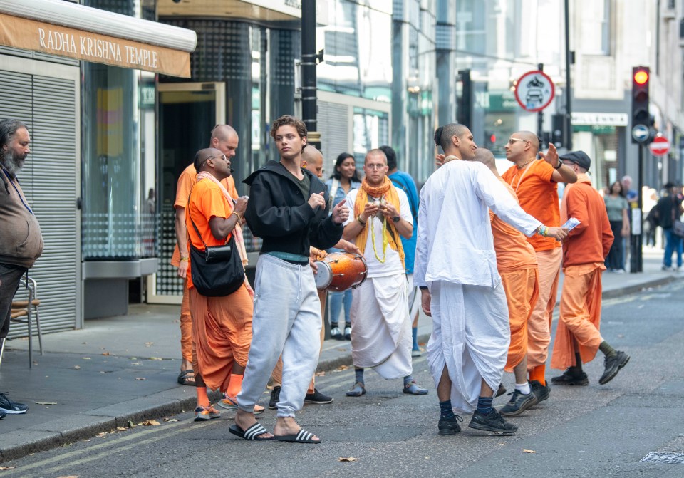 a group of people are walking down a street in front of a radha krishna temple