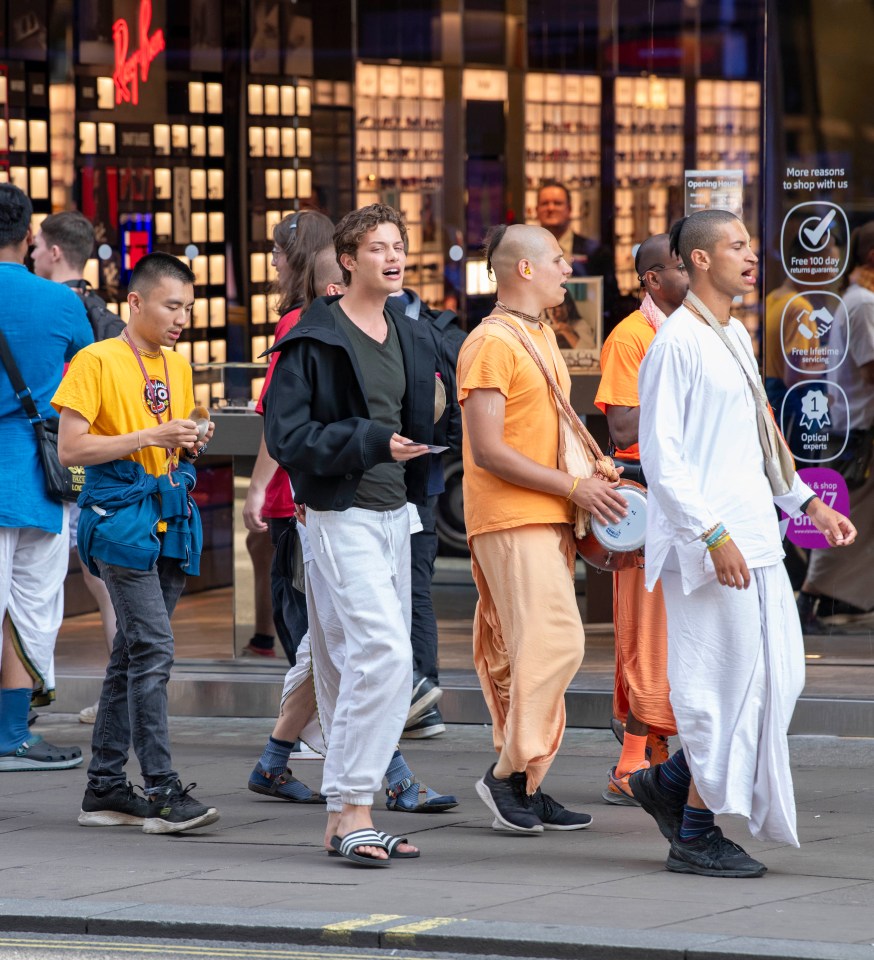 a group of people walking in front of a ray-ban store