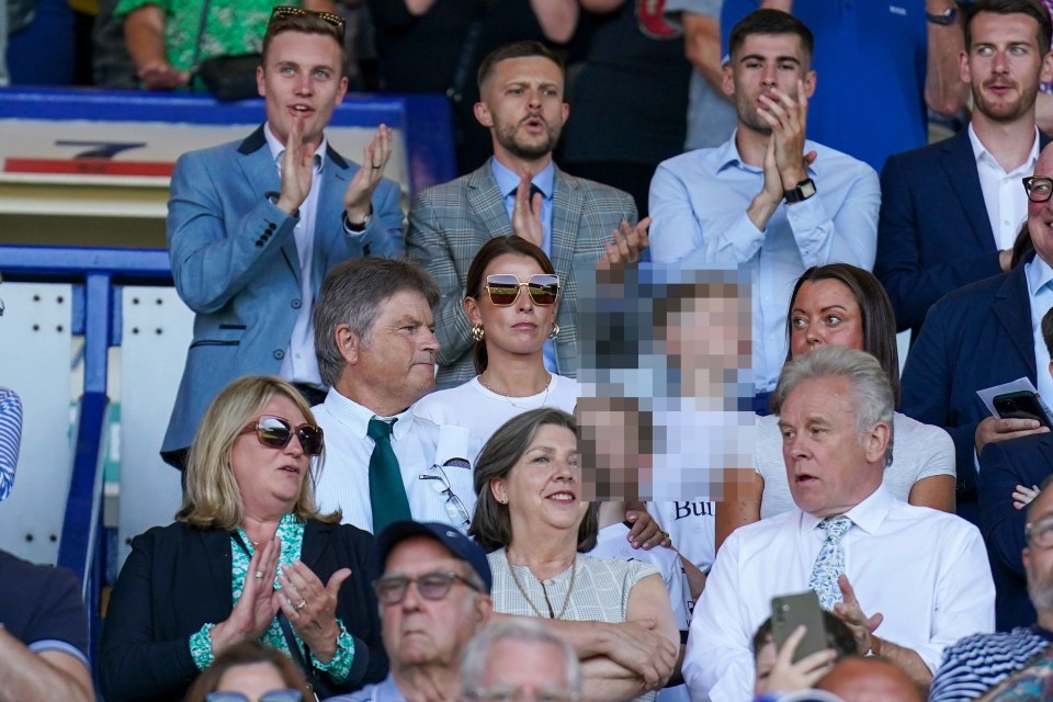 a group of people sitting in a stadium with one wearing a shirt that says bull