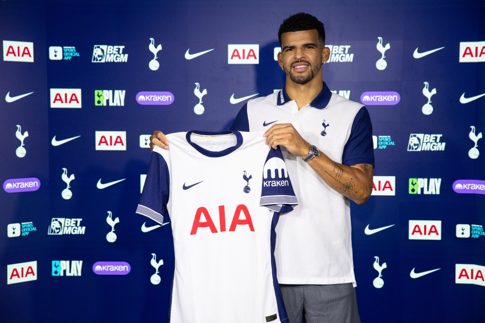 a man holds up a white aia jersey