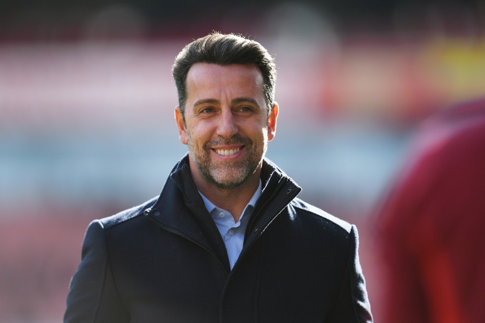 a man with a beard is smiling in front of a red stadium