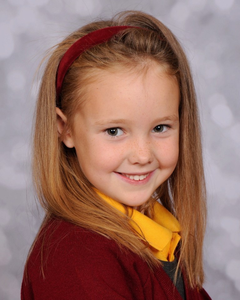 a young girl wearing a red headband and a yellow shirt smiles for the camera