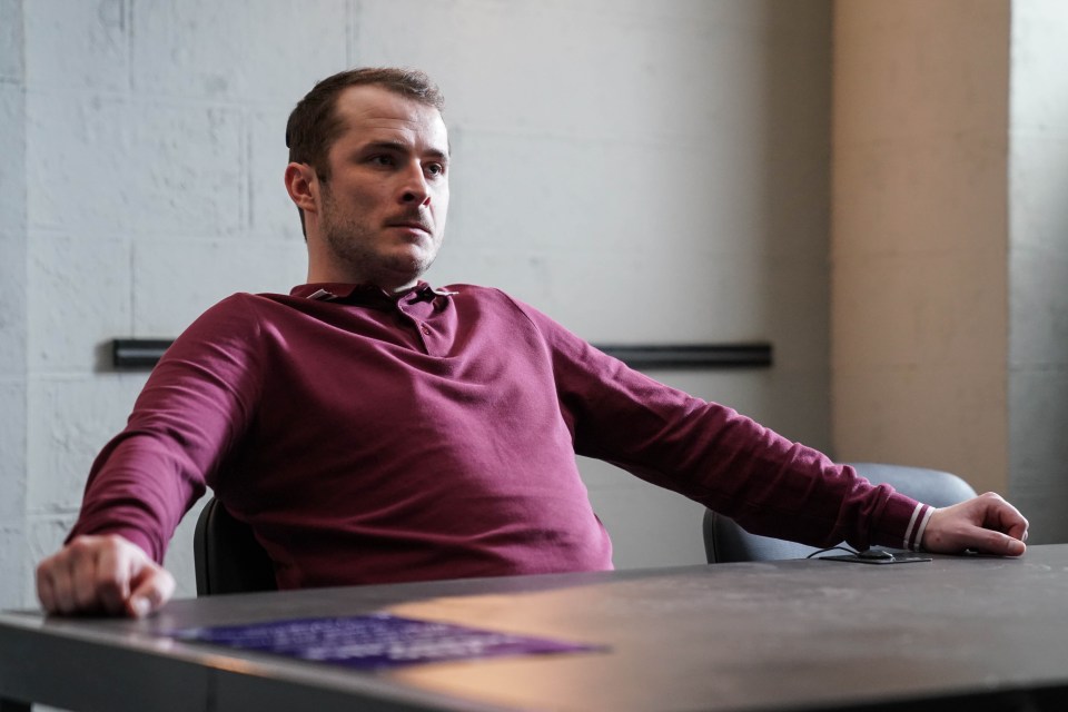 a man in a maroon shirt sits at a table