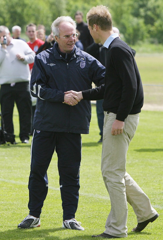 a man in an umbro jacket shakes hands with another man