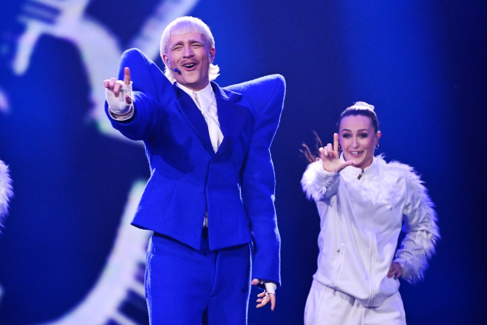 a man in a blue suit stands next to a woman in a white jacket