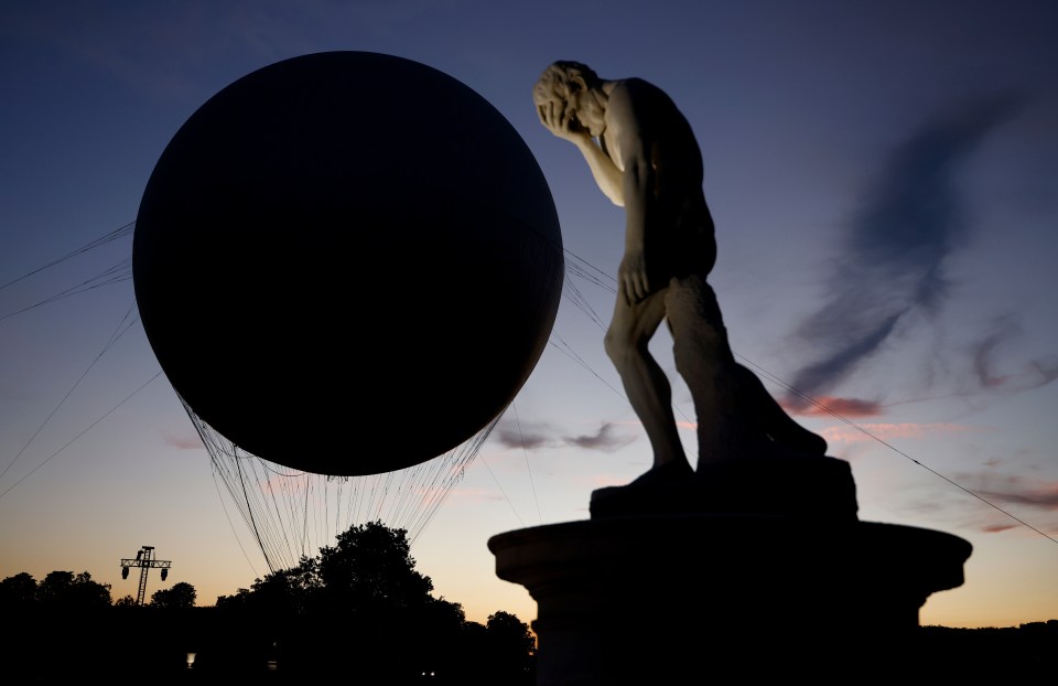 a statue of a man is standing in front of a balloon