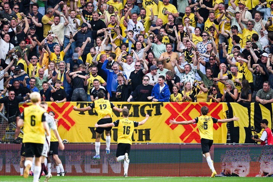 soccer players celebrate in front of a banner that says " zeigt "