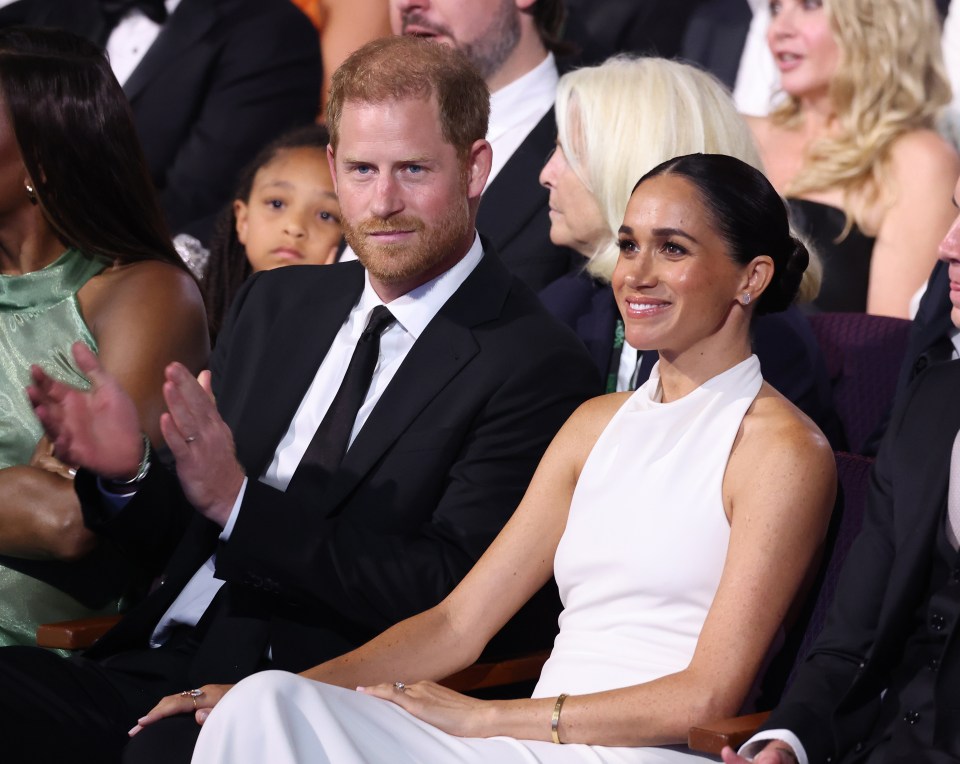 a man in a suit and tie sits next to a woman in a white dress