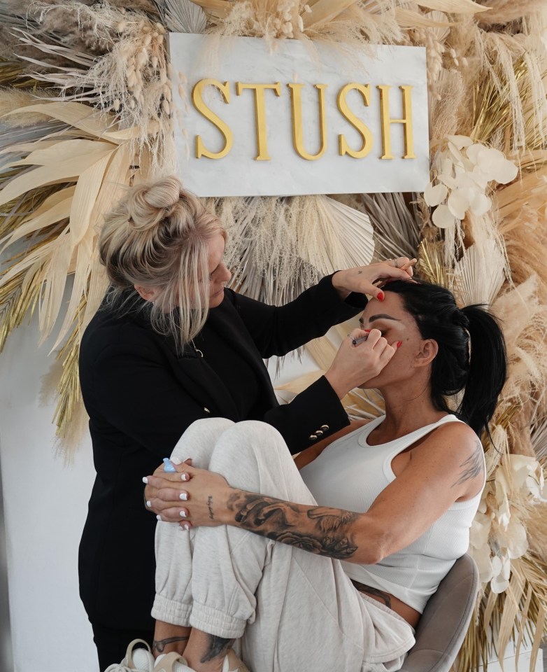 a woman is getting her makeup done in front of a sign that says slush