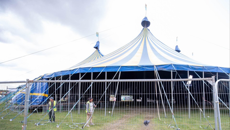 a large blue and white tent is behind a fence