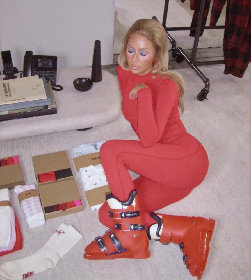 a woman in a red ski suit is kneeling on the floor