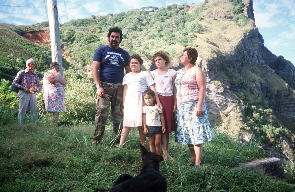 a group of people standing on top of a hill with a dog in the foreground