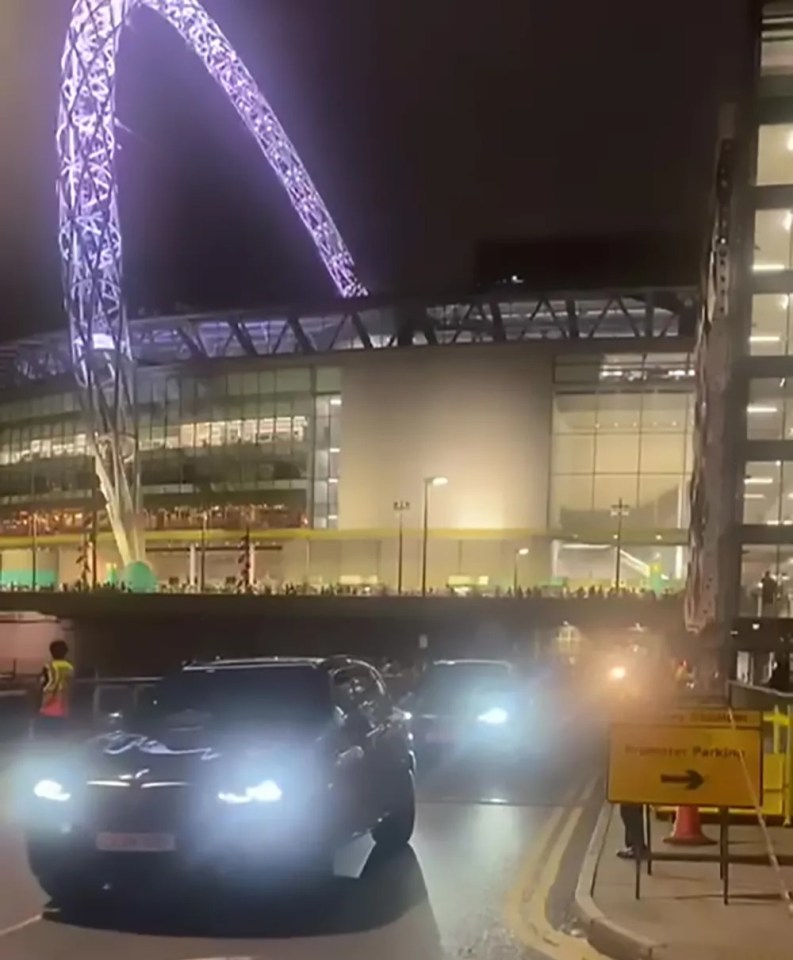 cars are driving down a street in front of a large building