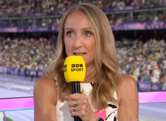 a woman is holding a microphone in front of a crowd in a stadium .