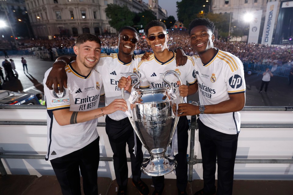 four soccer players holding a trophy with emirates fly better written on their shirts