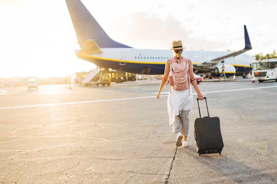 a woman walking with a suitcase in front of an airplane that says ryanair