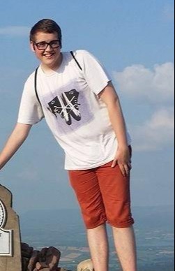 a young man is standing on top of a rocky hill .