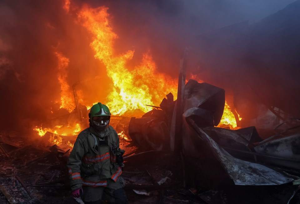 a fireman stands in front of a large fire