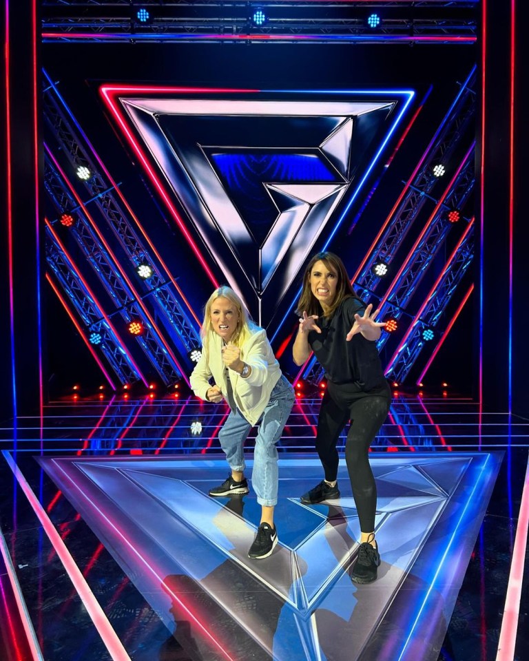 two women standing on a stage with a triangle in the background