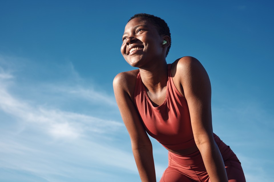 a woman in a red top is smiling with her arms outstretched