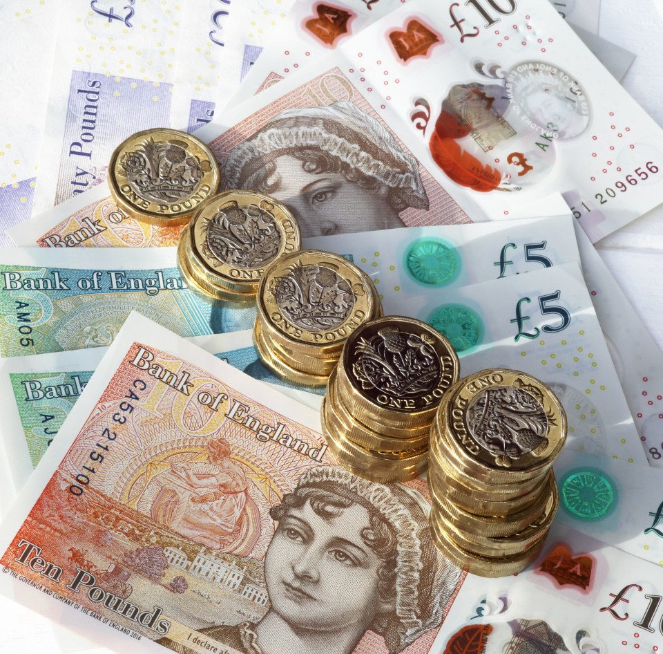 a stack of coins sits on top of a pile of bank of england notes