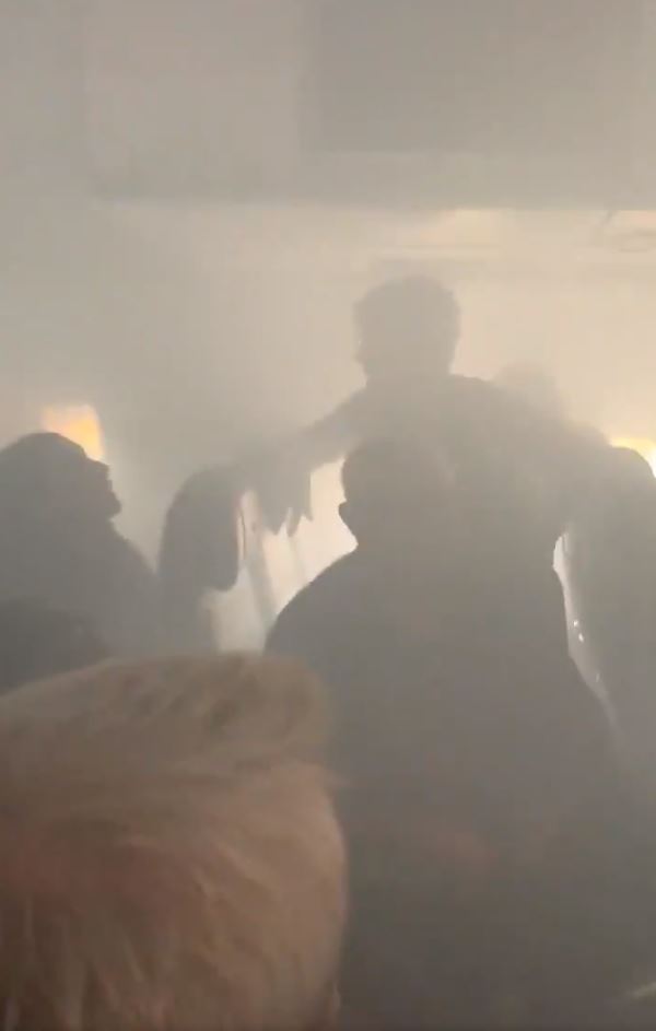 a group of people are standing in a room with smoke coming out of the ceiling .