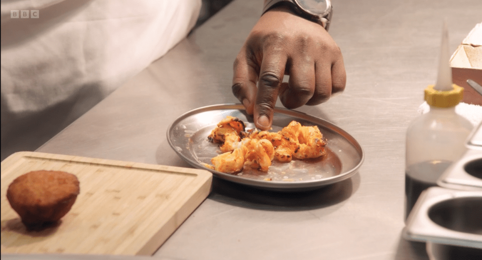 a bbc logo can be seen behind a person preparing food