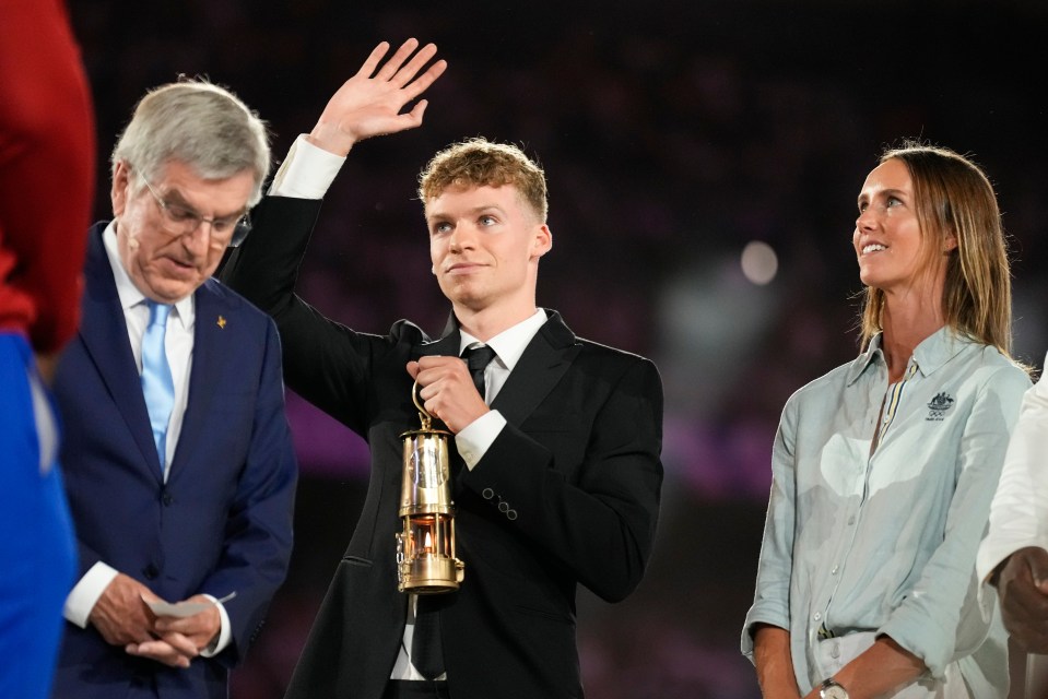 a man in a suit holds a trophy in his hand