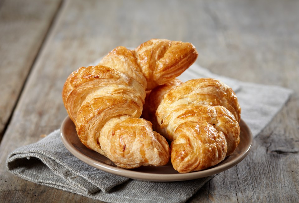 three croissants on a plate on a wooden table