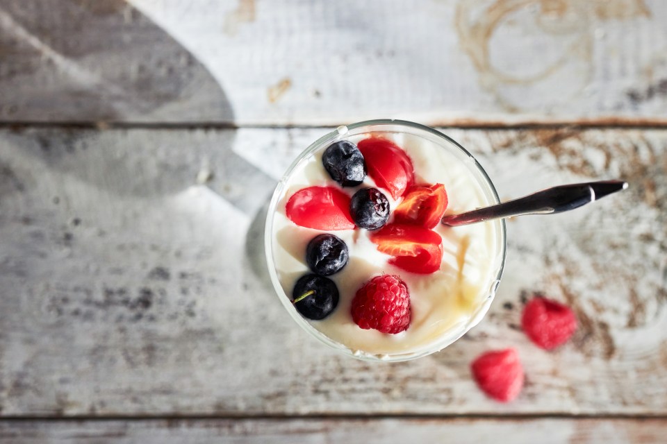 a glass of yogurt with berries and a spoon in it