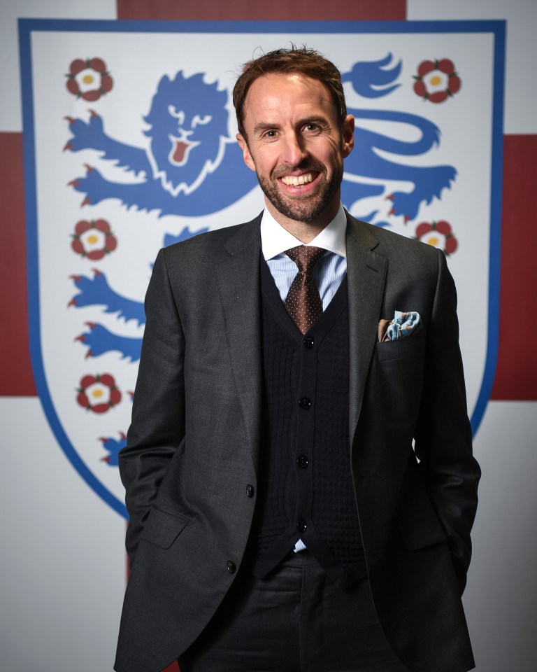 a man in a suit and tie stands in front of a shield with a lion on it