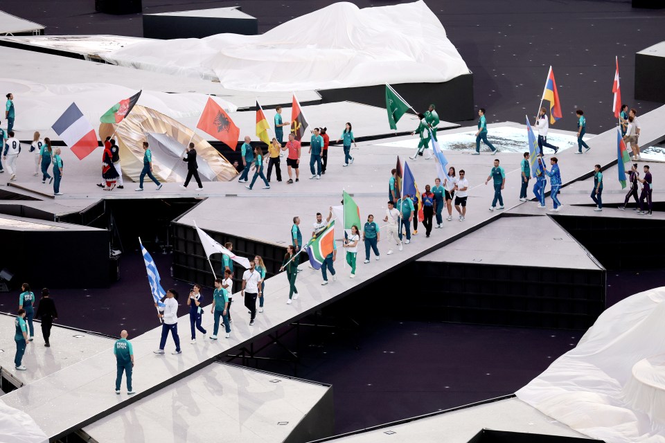 a group of people marching down a stage holding flags