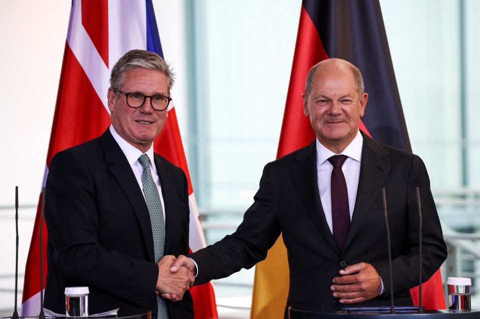 two men shaking hands with flags in the background