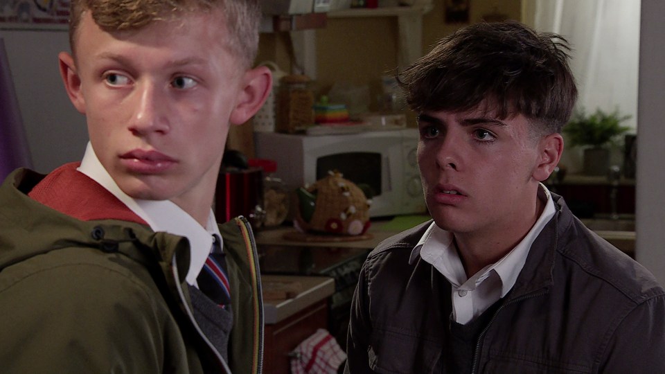 two young men are standing next to each other in a kitchen